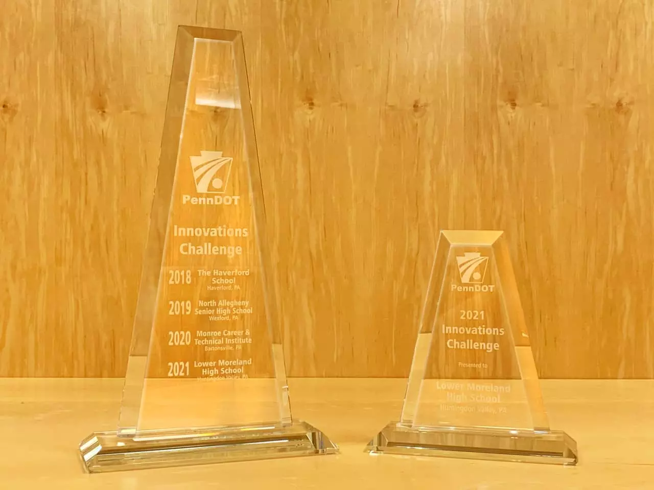 The Innovations Challenge traveling trophy showing winners from the past four years, next to the Lower Moreland High School 2021 Innovations Challenge trophy.